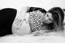 A pregnant woman laying on her bed