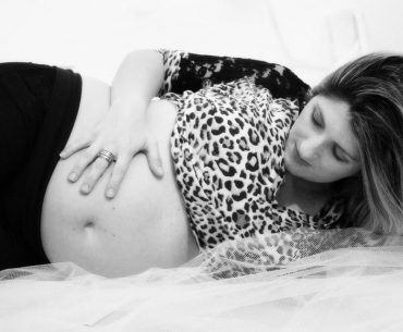 A pregnant woman laying on her bed